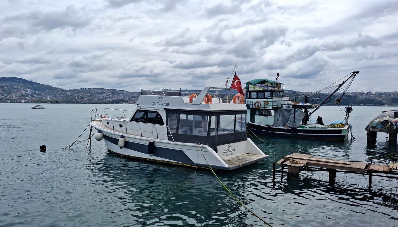 Yeniköy sahilinden kalkan küçük butik özel tekne, arkada Boğaz yalıları ve altın rengi öğleden sonra ışığı